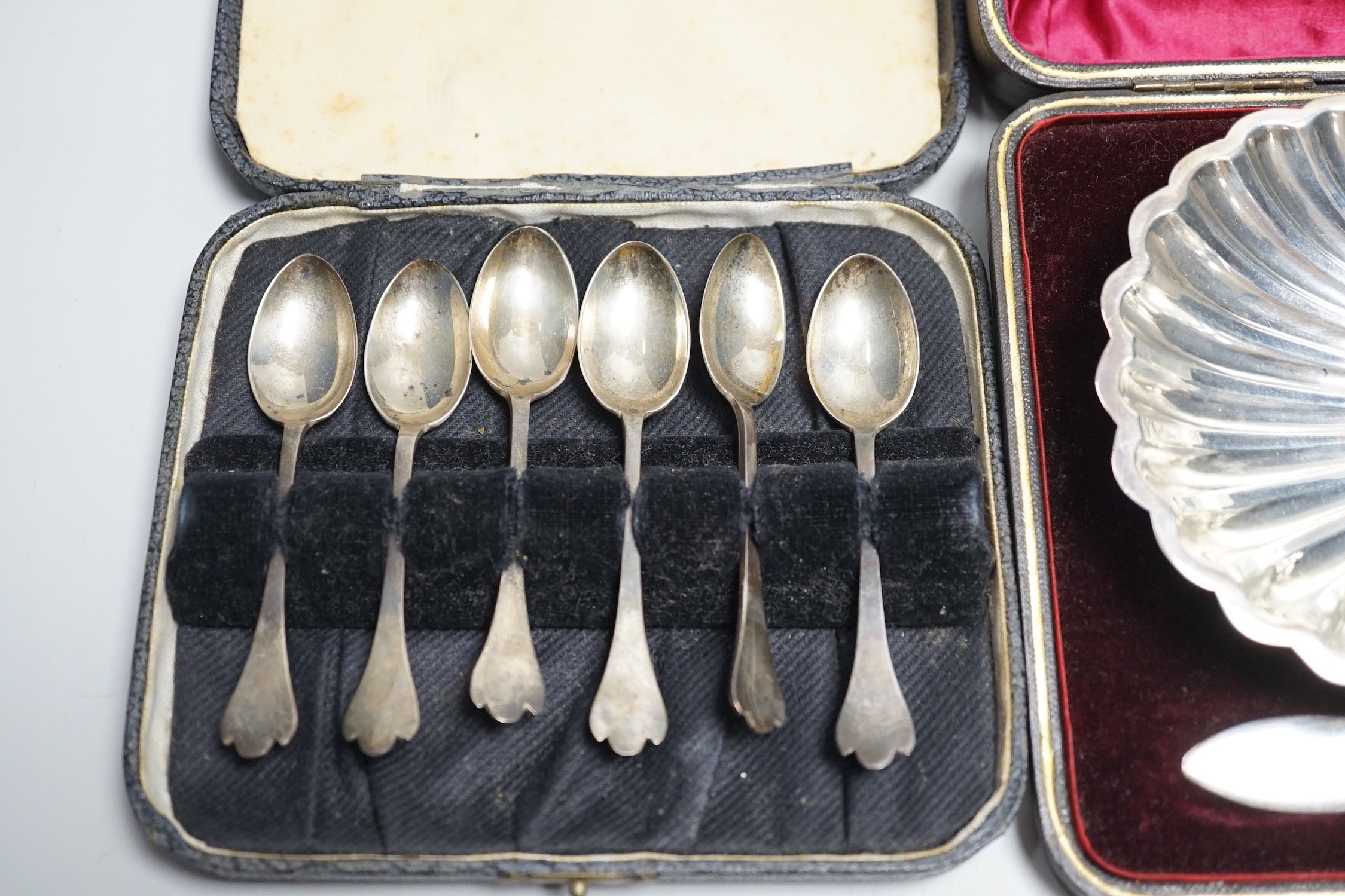 A set of six tea knives, an Edwardian silver butter shell and knife and a set of six silver coffee spoons, all cased.